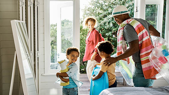 Family with body board and beach towel leaving beach house