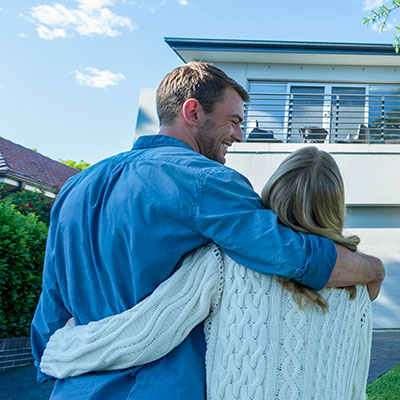 couple arms around each other in front of their house